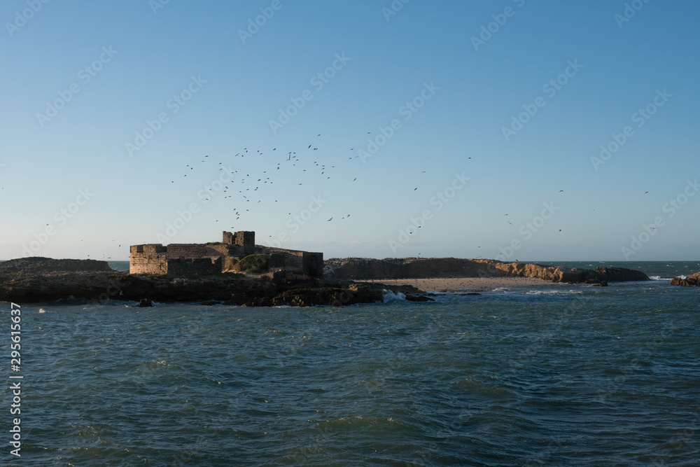 Walled city of Essaouira in Morocco on sunset with white waves splashes on the rocks and shallow depth of field Walled city of Essaouira in Morocco on sunset with white waves splashes on the rocks and shallow depth of field