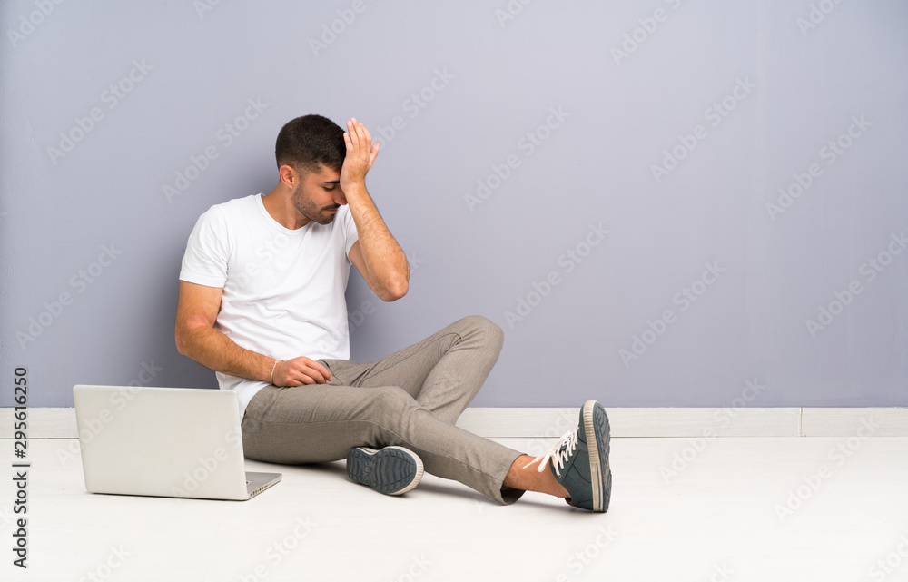 Young man with his laptop sitting one the floor having doubts with confuse face expression Young man with his laptop sitting one the floor having doubts with confuse face expression