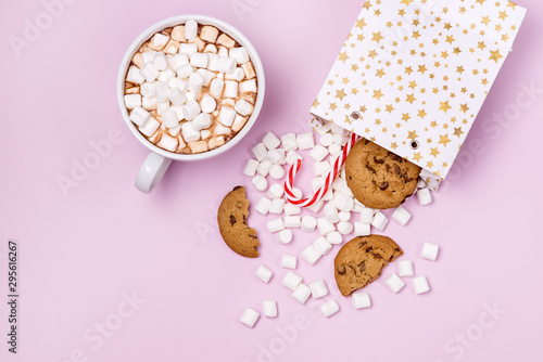 White Gift Shopping Paper Bags Full of Marshmellow aSweet Cookies and Candy Cane on Pink White Cup of Cocoa Background Shopping or Food Holiday Concept Copy Space photo