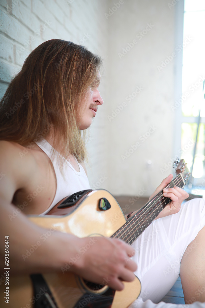 Fototapeta premium Young man with long hair with a guitar