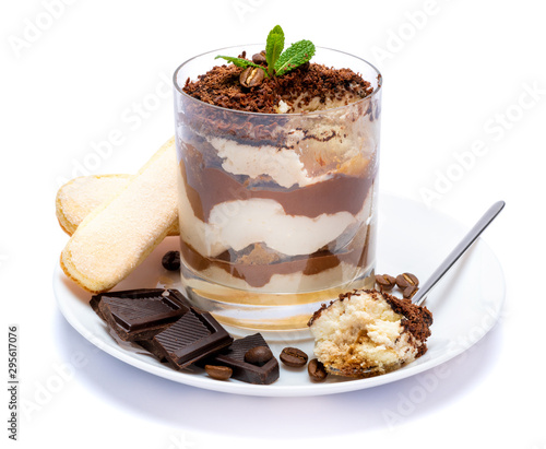 Classic tiramisu dessert in a glass cup on the plate and pieces of chocolate on white background with clipping path