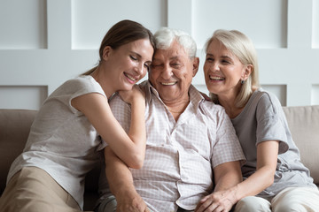 Cheerful three-generation family sitting on couch enjoy time together