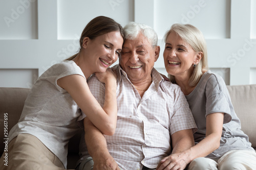 Cheerful three-generation family sitting on couch enjoy time together