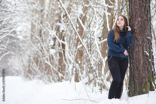 A young girl in a winter park on a walk. Christmas holidays in the winter forest. The girl enjoys winter in the park.