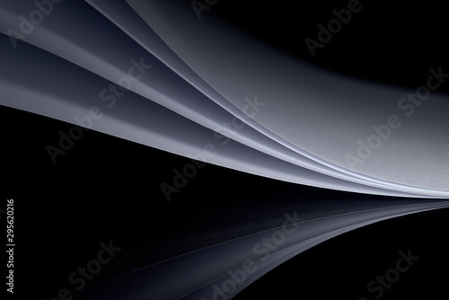 curved white sheets of paper against a dark background