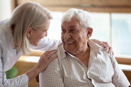 Caring nurse talking to elderly patient 80s man
