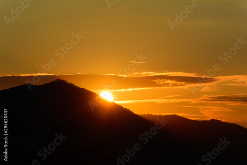 Silhouette di monti all alba con il sole che fa la sua comparsa dietro di loro