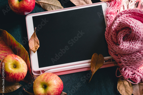 Cozy autumn, fall leaves,Tablet, Pink scarf knit from soft wool yarn on wood table, black old background, Seasonal, Morning sun light relaxing and still life concept, Selective focus photo