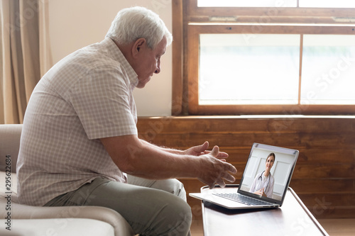 Senior man video chats with doctor online in telehealth visit photo