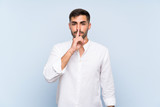 Handsome man with beard over isolated blue background showing a sign of silence gesture putting finger in mouth