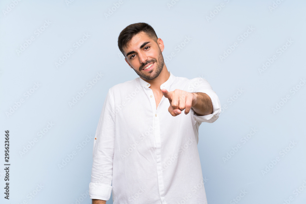 Handsome man with beard over isolated blue background points finger at you with a confident expression Handsome man with beard over isolated blue background points finger at you with a confident expression