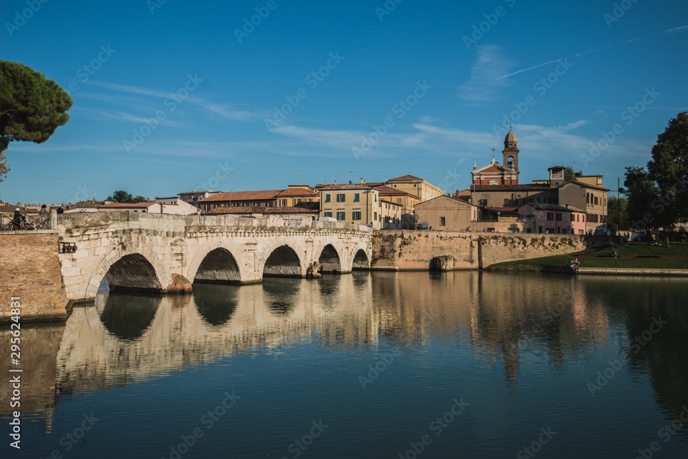 Rimini, Italy - September 11, 2019: Tiberius bridge in Rimini on a background of blue sky with white clouds