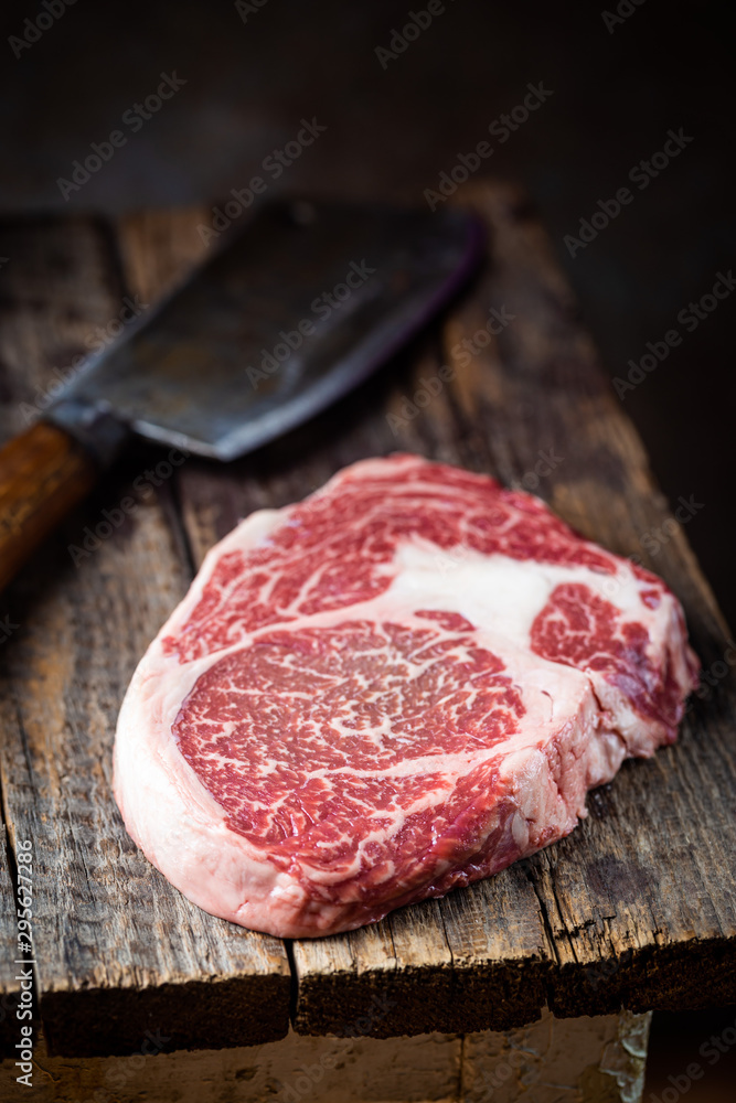 Raw fresh meat Ribeye Steak and seasonings on wooden background, rustic style