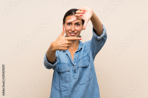 Young woman over isolated background focusing face. Framing symbol © luismolinero