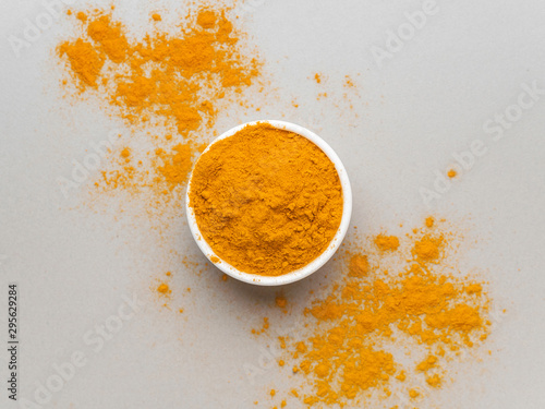 Fototapeta Naklejka Na Ścianę i Meble -  Turmeric powder. Traditional indian golden healthy spice in white ceramic bowl on gray background. Top view
