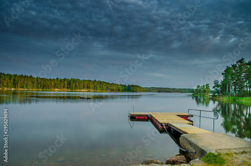 Peaceful tranquill view of dusky evening nature from a lake side with wooden floating bridge in the water during the summer in europe