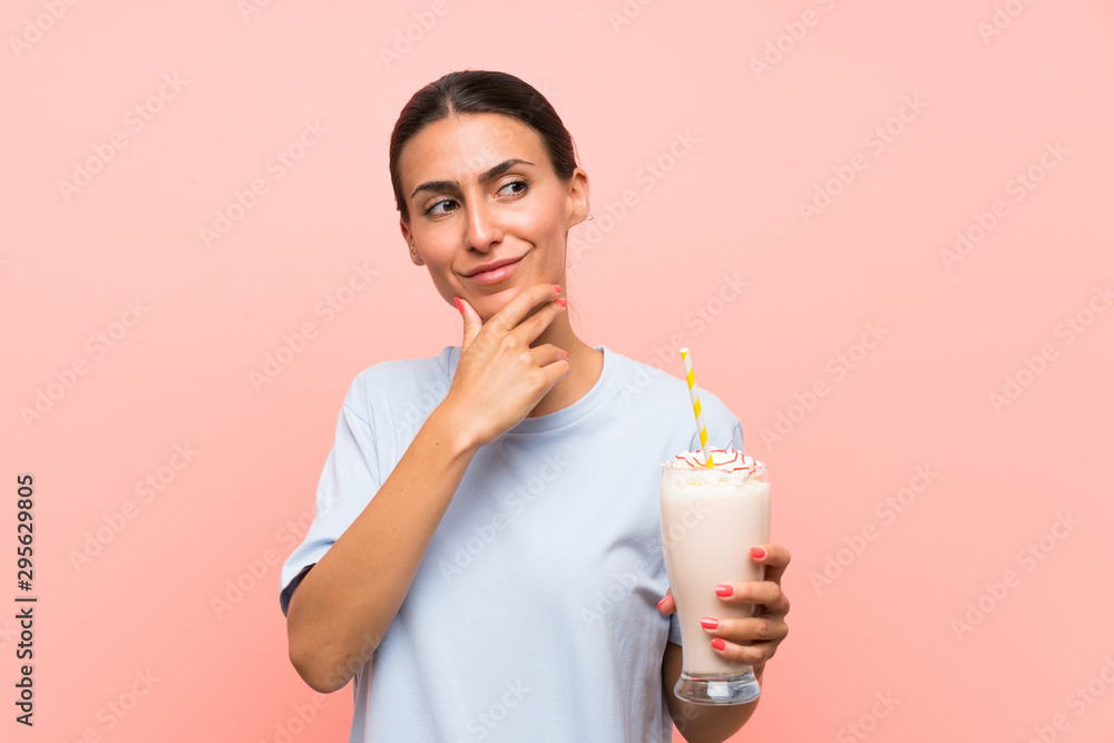 Young woman with strawberry milkshake over isolated pink background thinking an idea Young woman with strawberry milkshake over isolated pink background thinking an idea