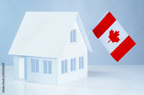 Model cottage with the flag of Canada. Moving to Canada. Real estate prices in Ottawa. Accommodation in Ottawa. Rent a cottage. Purchase real estate in another country.