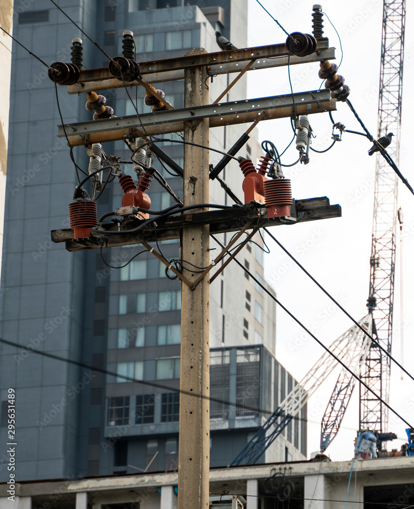 A high-voltage electricity pylons against buildings in the city.