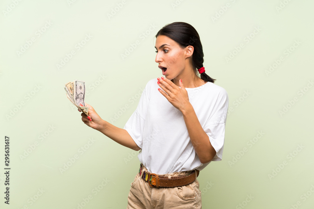 Young woman over isolated green background taking a lot of money Young woman over isolated green background taking a lot of money
