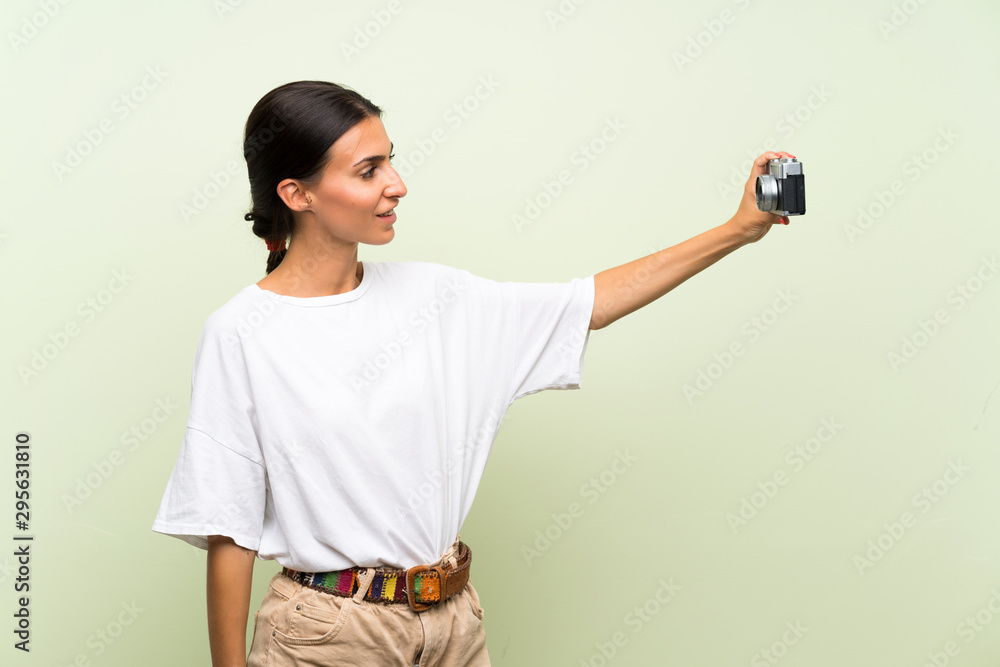 Young woman over isolated green background making a selfie Young woman over isolated green background making a selfie