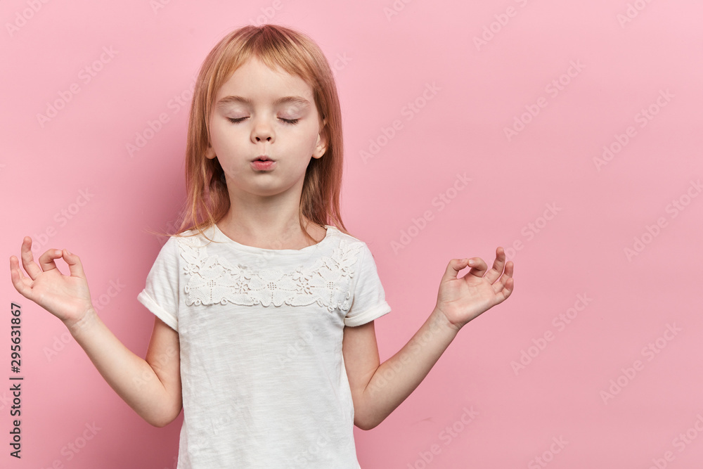 Little relaxed cute girl practicing yoga, isolated on pink. close up portrait, isolated pink background, health care, wellness. copy space