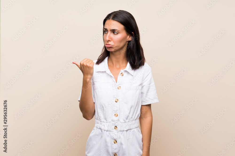 Young woman over isolated background unhappy and pointing to the side Young woman over isolated background unhappy and pointing to the side