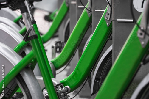 Street transportation green hybrid rent bicycles with electronic form of payment for traveling around the city stand in row on rental network parking lot waiting for cyclists to make bike trip.