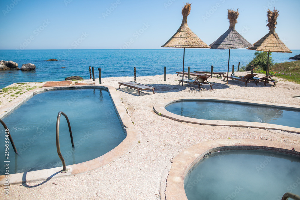 Fototapeta premium Blue water pools and straw umbrellas
