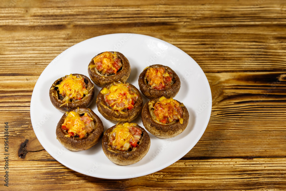 Baked mushrooms stuffed with minced meat, mushroom, paprika, onion and cheese on wooden table