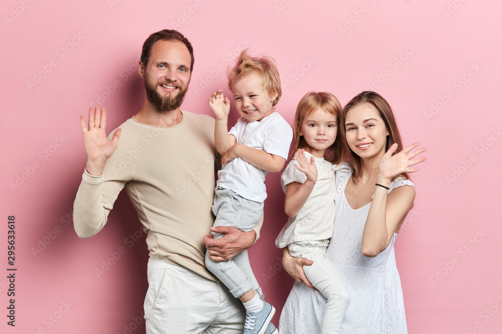 Happy young family with adoravle little daughters posing on pink background, close up portrait, solated pink background studio shot. relationship