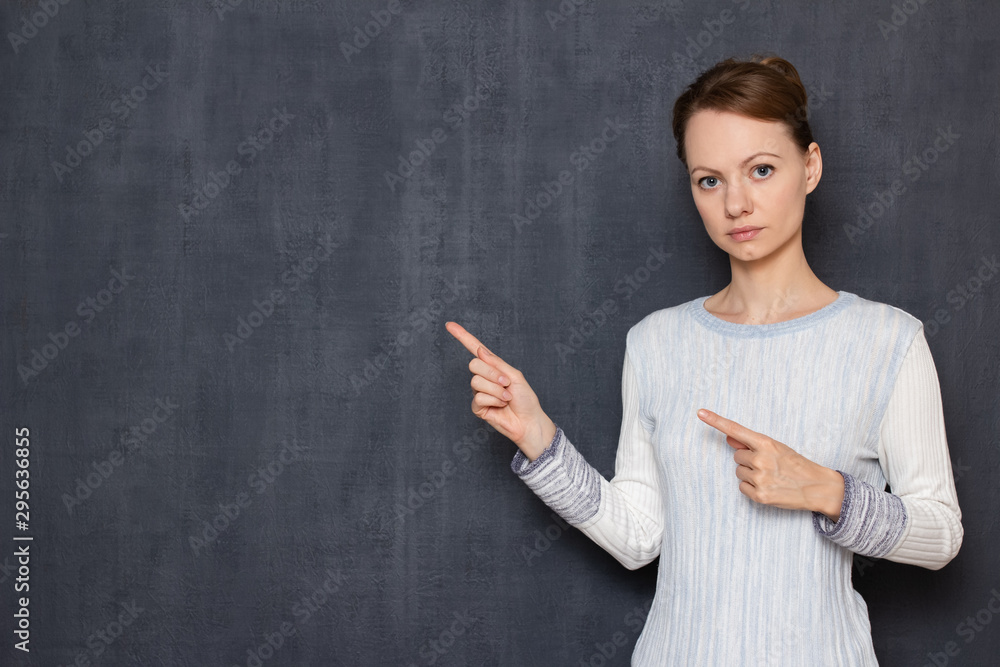 Portrait of serious focused girl pointing at copy space on left Portrait of serious focused girl pointing at copy space on left