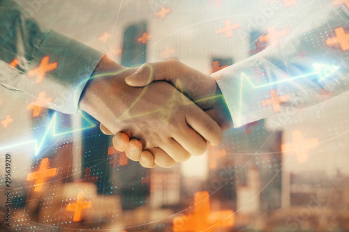 Double exposure of heart drawing on city view background with handshake. Concept of medical education