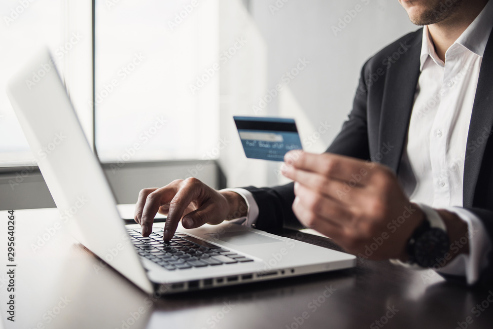 Man hand holding credit card and using laptop computer. Businessman or entrepreneur working at office. Online shopping, e-commerce, internet banking, finance concept Man hand holding credit card and using laptop computer. Businessman or entrepreneur working at office. Online shopping, e-commerce, internet banking, finance concept