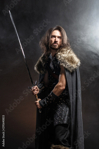 Portrait of a courageous ancient warrior in armor with sword and shield. Concept historical photo of bravery knight with long sword © Fotokvadrat