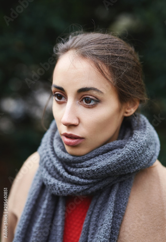 Close up autumn outdoor portrait of beautiful young woman in autumn park in knitted scarf.