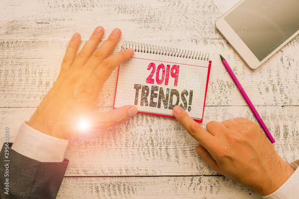 Obraz premium Text sign showing 2019 Trends. Business photo text general direction in which something is developing or changing Hand hold note paper near writing equipment and modern smartphone device