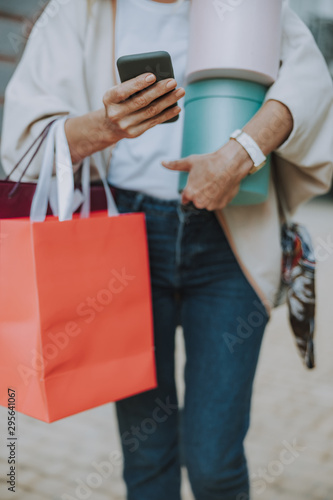 Caucasian woman holding bags and a smartphone