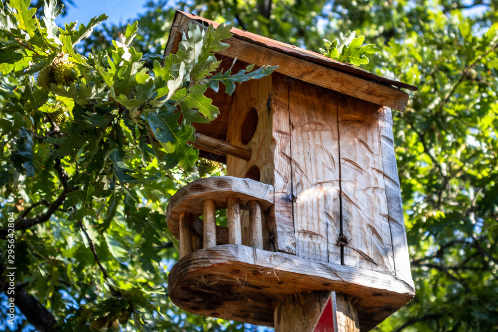 Beautiful wooden bird house next to the oak wood Beautiful wooden bird house next to the oak wood