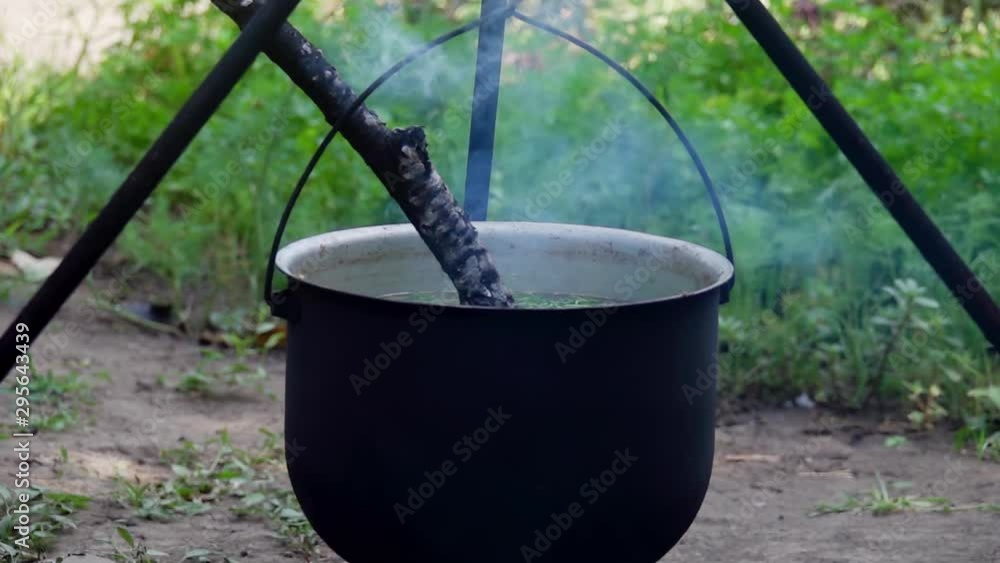 Cooking Fish Soup on Fire in Dark Iron Pot Cooking Fish Soup on Fire in Dark Iron Pot