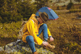 backpacker in green hat, yellow coat laces shoes, preparing for walking. cose up side view photo. copy space, tent in the background of the photo