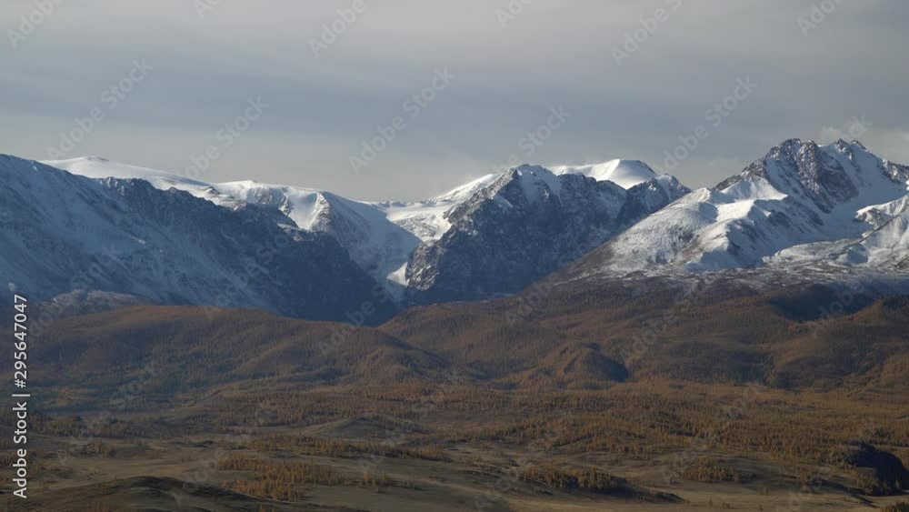 Beautiful panoramic shot of snowy Altai mountains peaks on cloudy sky background. North Chuya ridge.
