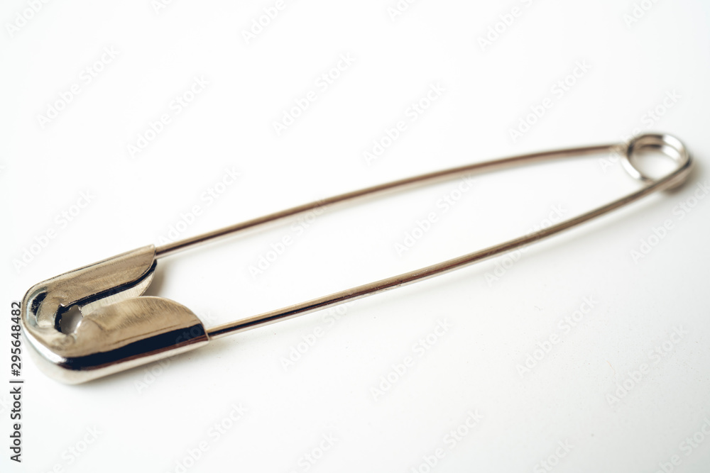 Macro metall safety pin for crafts, fashion, jewelry, hobby or household on white background with selective focus Macro metall safety pin for crafts, fashion, jewelry, hobby or household on white background with selective focus