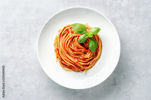 Canvas Print Top view of plate with spaghetti in tomato sauce and basil on white background