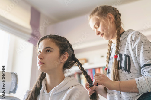 girlfriend teen braids pigtail in room on day off, light from window photo