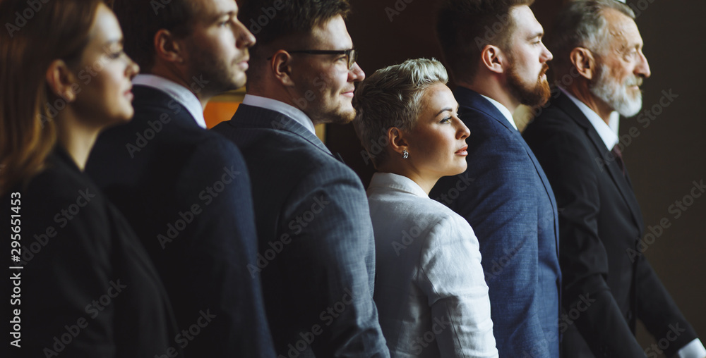 Obraz premium Noble attractive business people are taken a photo on dark background standing shoulder to shoulder. Dreamy handsome men in nice spectacles stands with friendly smile looking away, portrait, close up