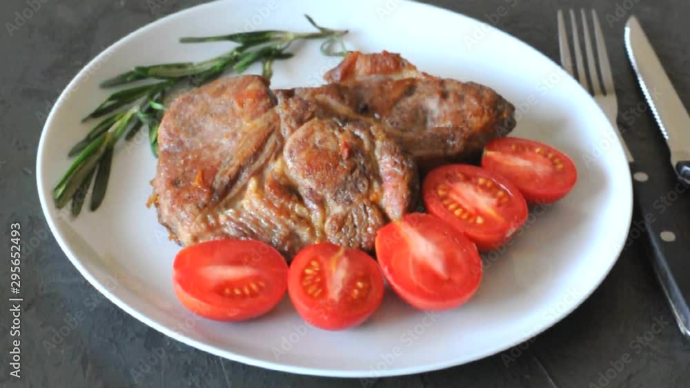 Grilled pork meat steak on a plate with tomatoes and rosemary Grilled pork meat steak on a plate with tomatoes and rosemary