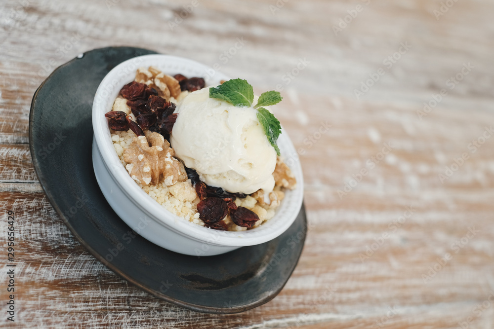 Apple crumble dessert with vanilla ice cream on the top on wooden table Apple crumble dessert with vanilla ice cream on the top on wooden table