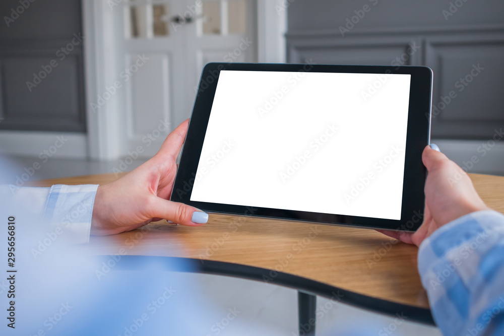 Over shoulder closeup view: woman hands holding digital tablet computer device with white blank screen in home interior. Mock up, copyspace, template, entertainment and technology concept Over shoulder closeup view: woman hands holding digital tablet computer device with white blank screen in home interior. Mock up, copyspace, template, entertainment and technology concept