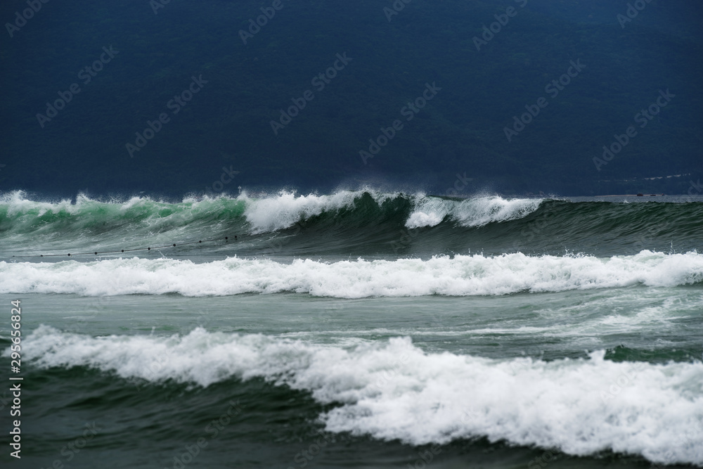 Stormy sea view near coastline against dark background. Waves and splashed drops.